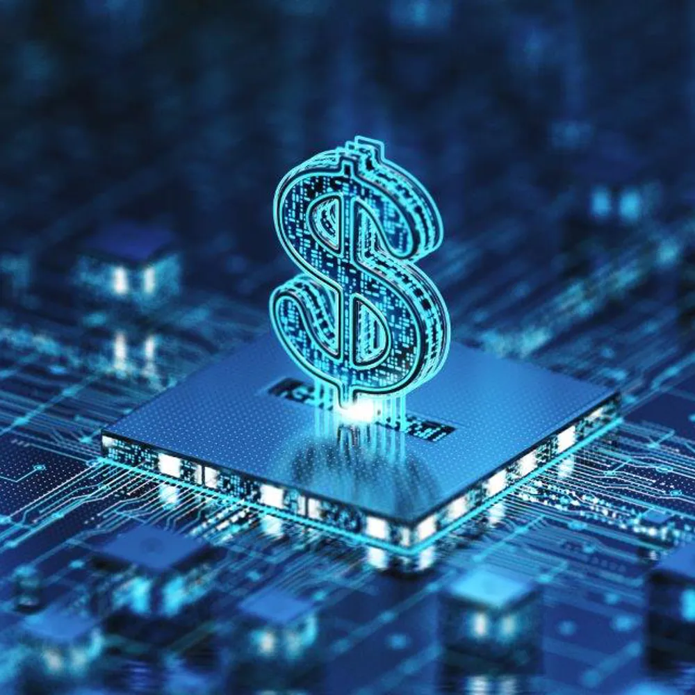Alt Text: A glowing blue dollar sign sits on top of a microchip, surrounded by a circuit board with various digital components. The image represents the intersection of finance and technology, such as fintech, digital currency, or AI-driven economic systems.