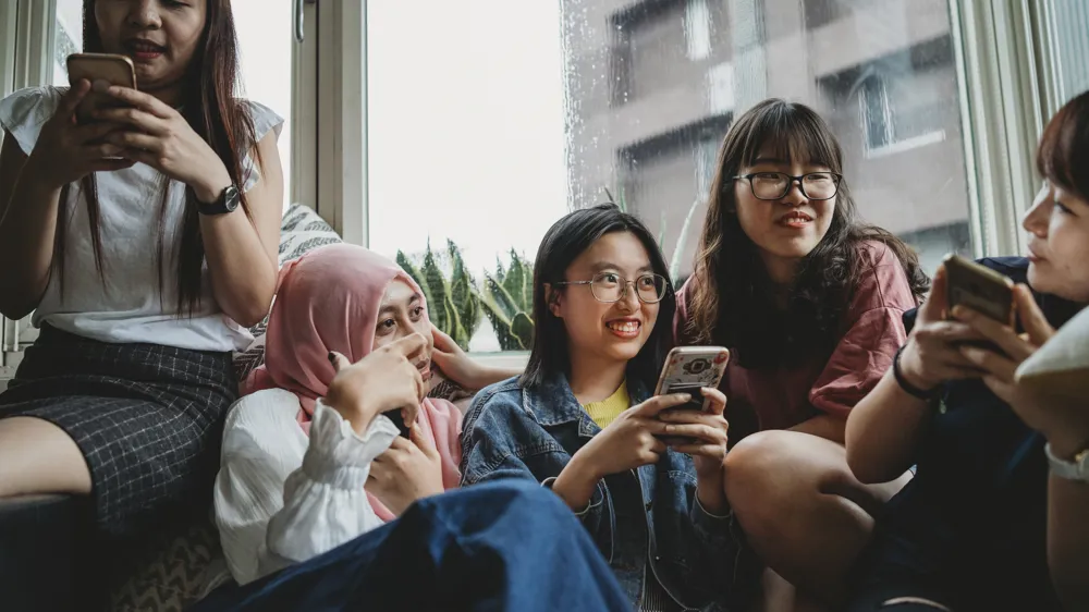 Alt Text: Group of young women using mobile phones together