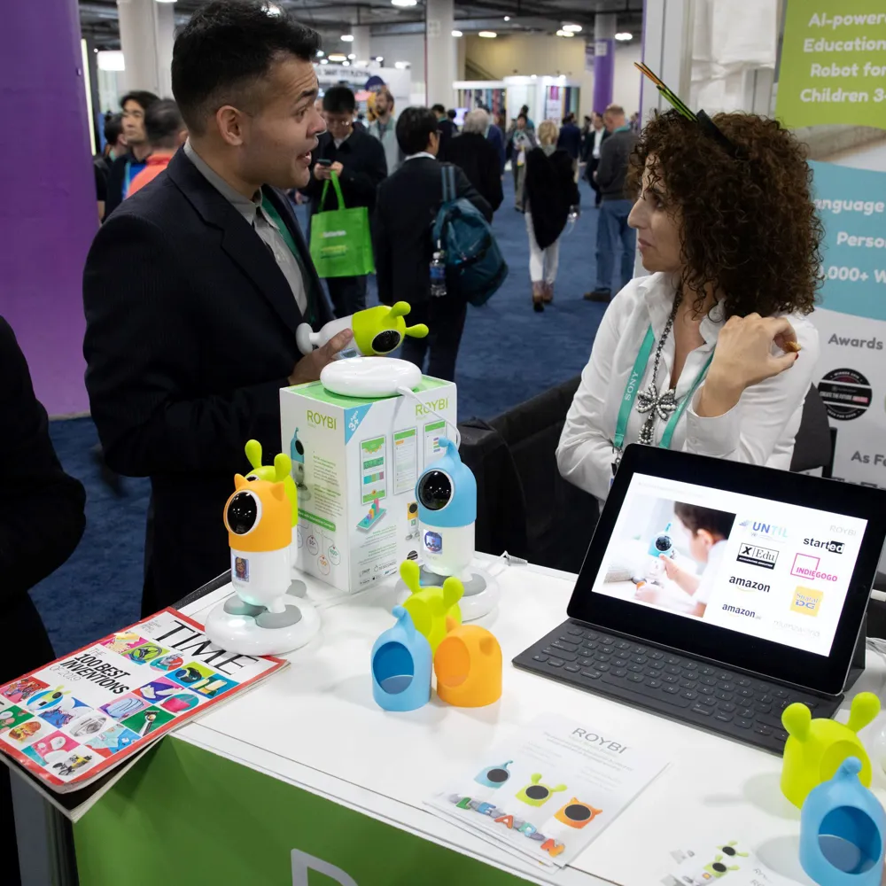Alt Text: ROYBI exhibit boot at CES 2020 in Eureka Park. ROYBI representative speaking with attendee about ROYBI educational robot.