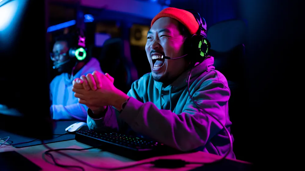 Alt Text Cheerful gamer celebrating his success after winning in video game over PC in gaming club.