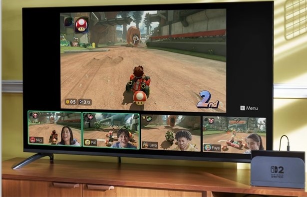 Alt Text:  A television displays a split-screen racing video game with multiple players visible, connected to a Nintendo Switch dock on a wooden TV stand.