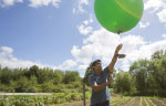 Researcher with a weather baloon in a planted field